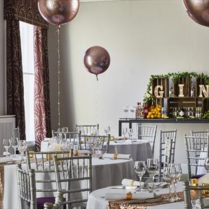 A room at the Durham Marriott set up for a Christmas Party with balloons and table decorations