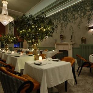 The Dining Room at Seaham Hall Hotel with tree decorations and candlelit tables. 