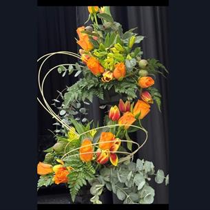 A flower arrangement with orange flowers and greenery.