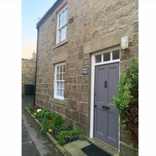 Exterior of Firethorn cottage. A stone building with grey wooden door