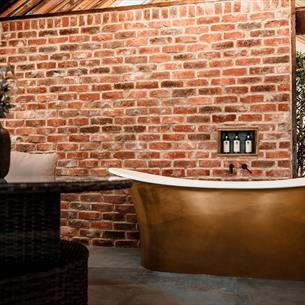 High ceilings, wood panelling, bespoke candle chandeliers and a large free-standing bath against the exposed brick wall.