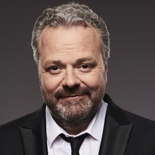 Headshot of Hal Cruttenden wearing a suit and smiling.