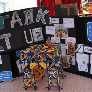 Engineering and maths-related activities in front of a sign which reads, 'Crank It Up!'