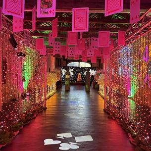 Playing cards suspended from beams in an illuminated, colourful tunnel