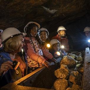 Children wearing hard hats in Killhope Lead Mine in dark truck full of rocks 