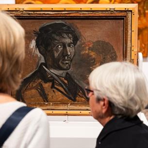 Two women with grey hair looking at a self portrait by Norman Cornish