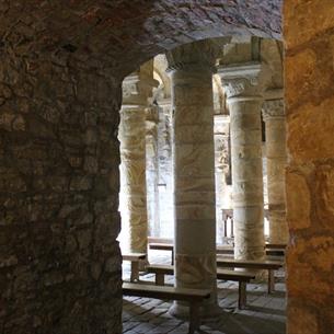 Photograph looking in to the Norman Chapel and Durham Castle, showing several illuminated stone columns beside thick stone walls