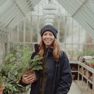 A woman standing in the greenhouse and holding a plant at Raby Castle