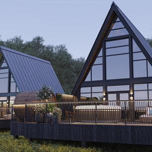 Exterior View of Treehouses set in woodland with full height windows which allow natural light to flood in and wrap around balcony with sunken hot tub