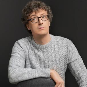 Luke Connell resting his arm on a chair and glancing sideways. 