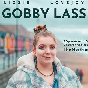 Lizzie Lovejoy, 'Gobby Lass' wearing colourful eyeshadow, standing at the beach, next to vibrant beach houses 