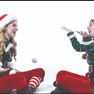 Two elves laughing and playing with a snowball.