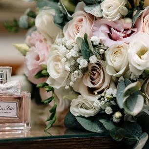 Image of a pink and white wedding bouquet next to some Dior perfume at South Causey Inn.