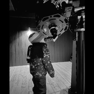 A young child looks through the eyepiece of a telescope.