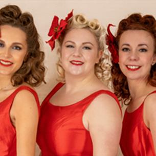 The Darling Dollies posing for a photo in red vintage dresses with vintage hair and makeup.