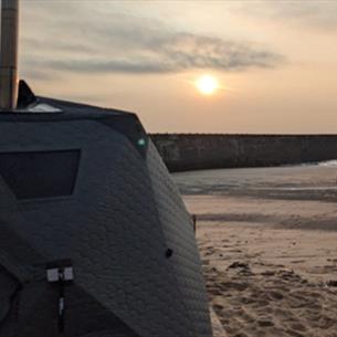 Beachgoers at sunrise on the beach in Seaham heading to the sauna