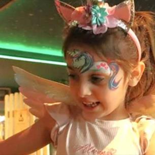 Little girl with fairy wings and a unicorn painted on her forehead