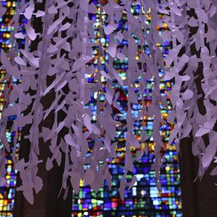 Paper peace doves hanging in front of stained glass windows