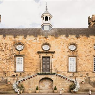 An entrance to Lumley Castle, two floral staircases leading to a door.