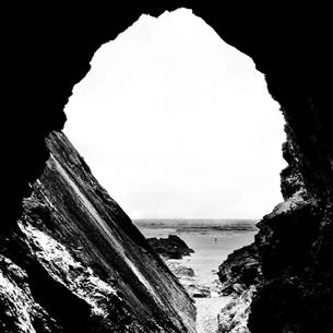 Black and white image of a cave opening out to sea.