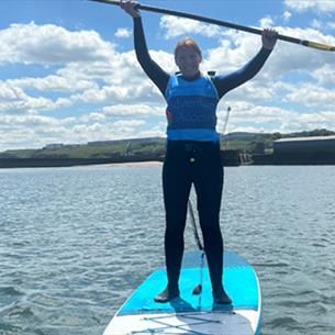 SUP paddleboarder on the water with oar held above her head