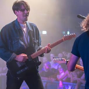 Jonny, lead singer of Sham Fender, and a band member performing to an audience.