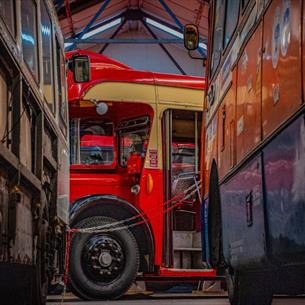 A red vintage bus parked between two others