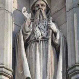 An ornate marble statue of a hooded figure connected to a church