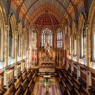 The interior of an extravagant chapel, with stained glass windows surrounding it 