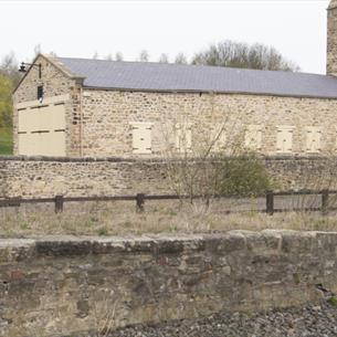 A large stone train shed surrounded by trees