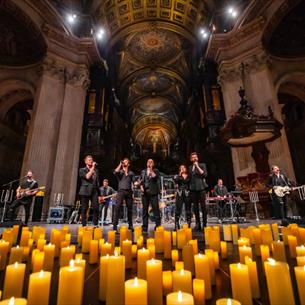 Live performers on stage in a candlelit cathedral.