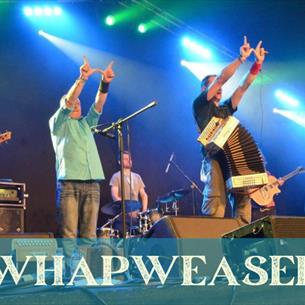 Eight people on stage with folk instruments, making the letter 'W' with their hands, the text 'Whapweasel' underneath.