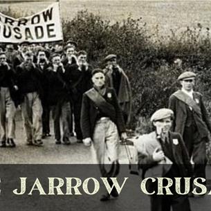 Historical photo of the Jarrow Crusade, a group of people walking down the road with a large banner.