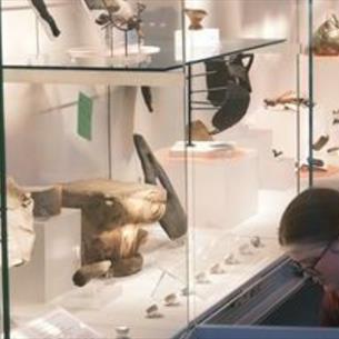 A museum exhibit with lots of old artefacts with a person tending to them in the right hand corner.