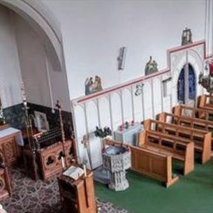 Birds eye view of an ornate church with an altar and pews.