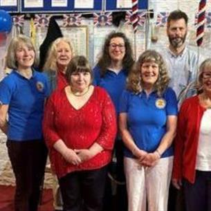 A group of eight people wearing red and blue in the ringing chamber of a church.
