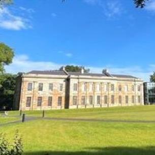 Historical stone building with a grass lawn in front.