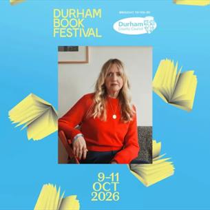 A person in a red jumper sat on a chair, on a light blue background surrounded by books. 