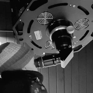 A young child looks through the eyepiece of a telescope.