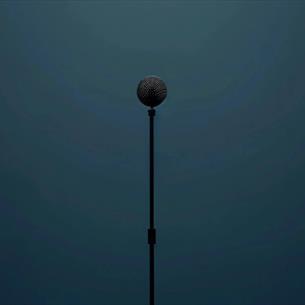 A black microphone and stand on a navy background