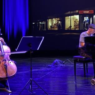 Two people on stage playing the cello and piano.