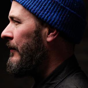 Side profile of a person wearing a blue hat surrounded by darkness.