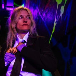 A person looking off to the side wearing a suit on a dark staircase.