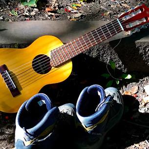 Guitar and a pair of walking boots, on a woodland step