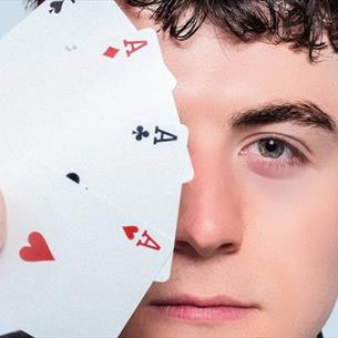 Person holding a fan of cards over their eye, against a light blue background