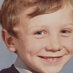 School photo of a small child, smiling against a grey background