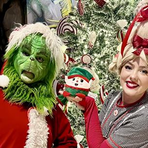 Mr. Grinch and Cindy-Lou posing for a photo in front of a Christmas tree at Lanchester Garden Centre.