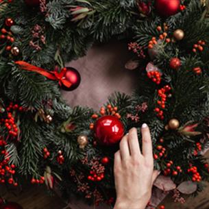 A handmade wreath with red berries and baubles.