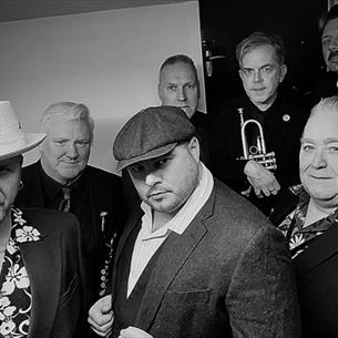 The Revolutionaires & Tyne Valley Big Band stood in a group looking at the camera. The image is in black and white.