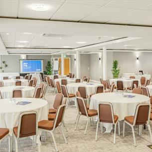 Room set out for a conference with round tables and chairs